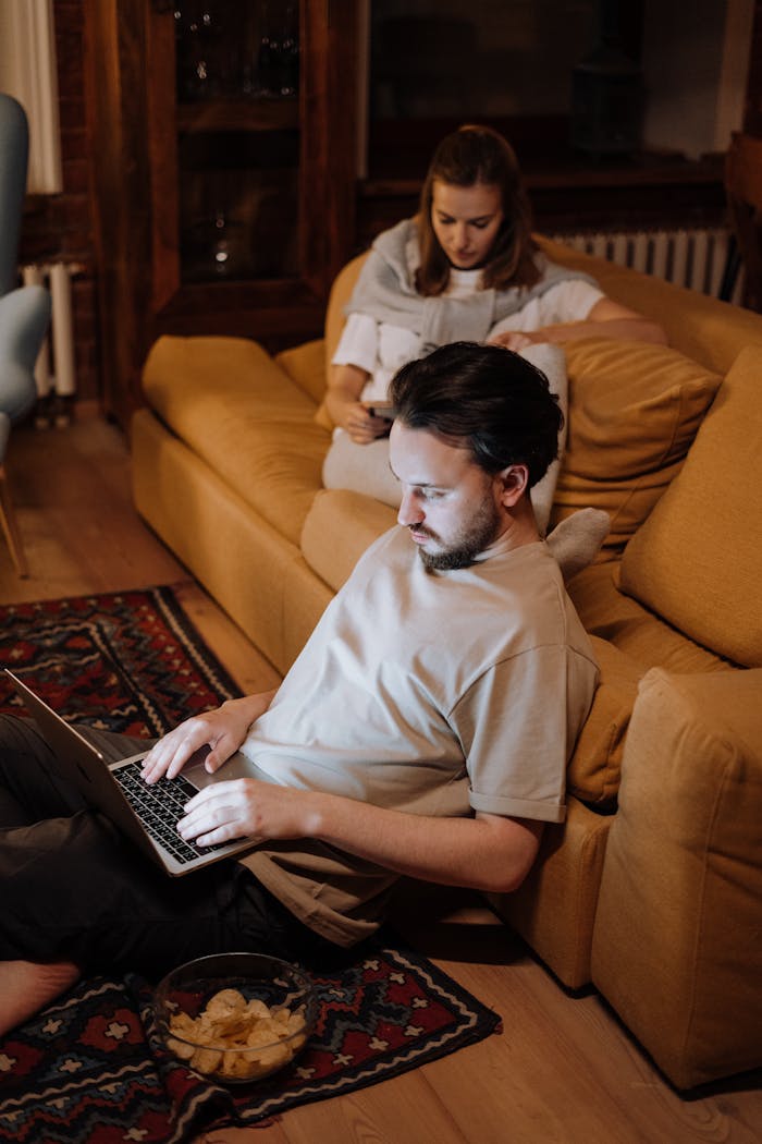 Man in White Crew Neck T-shirt Sitting on Brown Sofa